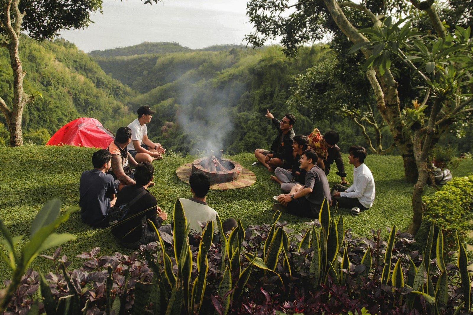 People gathered around a fire in a tropical landscape